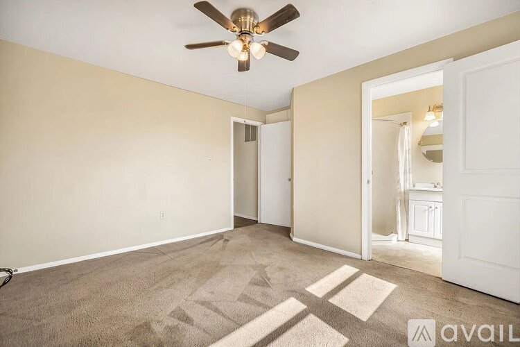 A room with a fan and a rug on the floor.