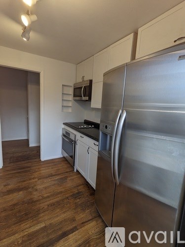 A kitchen with a stainless steel refrigerator and wooden floors.