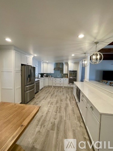 A modern kitchen with wooden floors and white cabinets.