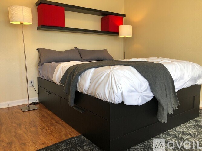 A bed with a white comforter and a grey blanket is in the room.