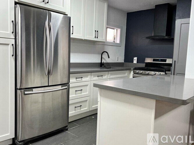 A modern kitchen with a stainless steel refrigerator and white cabinets.