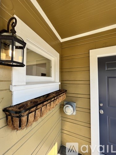 A black lantern hangs on a beige wall next to a blue door.