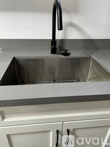 A kitchen sink with a black faucet and a metal drain.