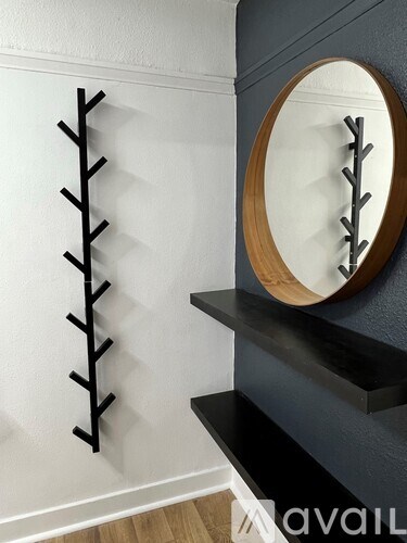 A wall with a mirror and a shelf with a black frame.