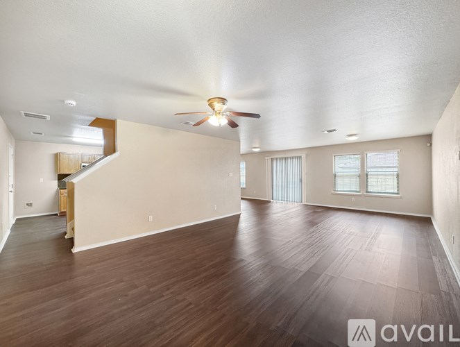 A spacious room with wooden floors and a ceiling fan.
