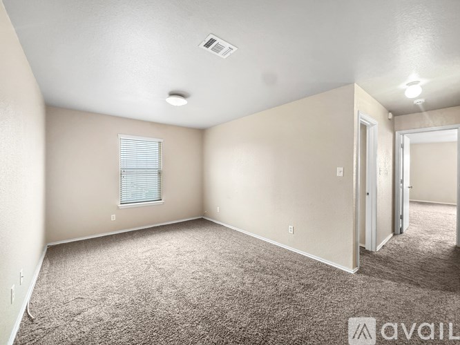 A spacious room with beige walls and carpeted floor.