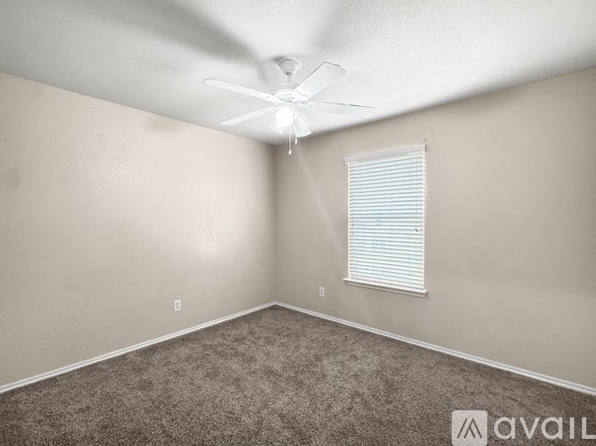 A room with a ceiling fan and a window with blinds.