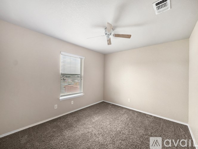 A room with a ceiling fan and a window with blinds.