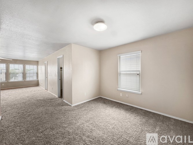 A spacious room with carpeted floor and a window with blinds.