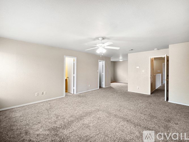 A spacious room with a carpeted floor and a ceiling fan.