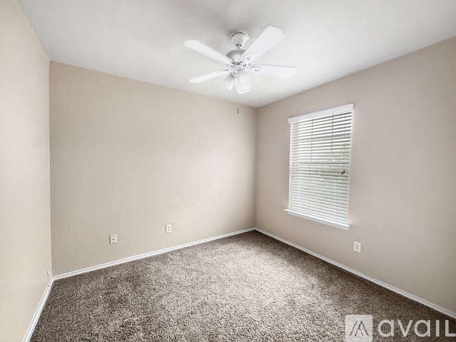 A room with a ceiling fan and carpeted floor.