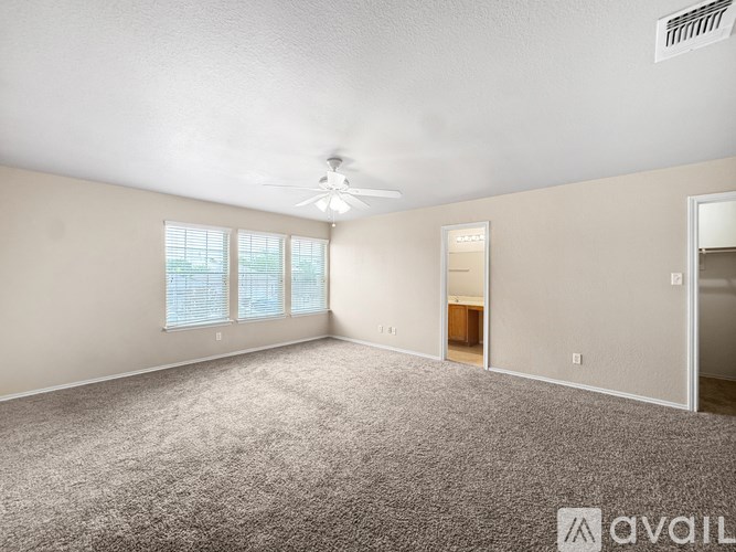 A spacious room with a carpeted floor and a ceiling fan.