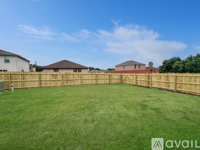 A backyard with a wooden fence and a green lawn.