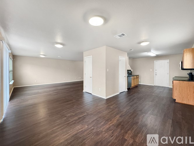 A spacious room with wooden flooring and white walls.