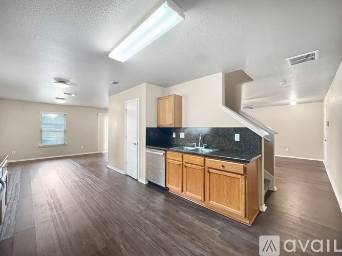 A spacious kitchen with wooden cabinets and a black countertop.