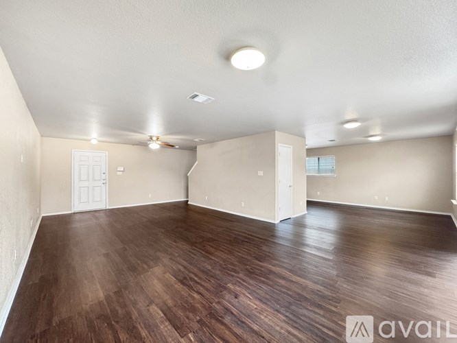 A spacious room with wooden flooring and white walls.