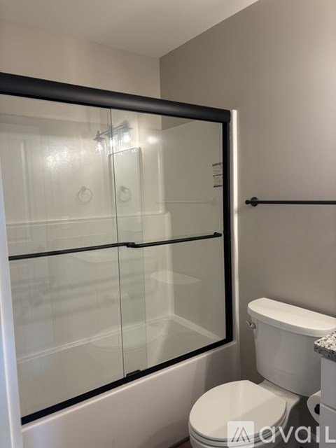 A white toilet sits next to a glass shower door in a bathroom.