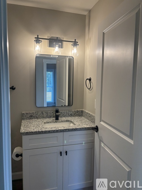A bathroom with a granite countertop and a mirror above it.