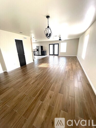 A room with wooden flooring and a chandelier hanging from the ceiling.