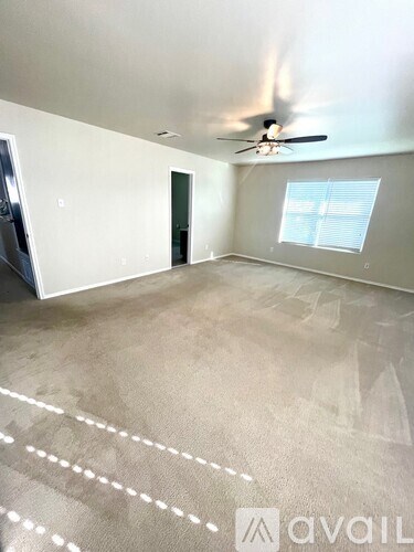 A spacious room with a ceiling fan and a window with blinds.