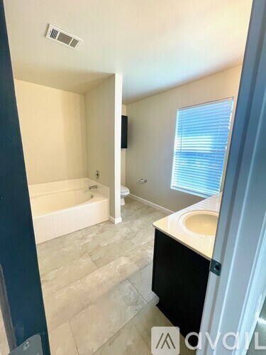 A bathroom with a tub, sink, and window.
