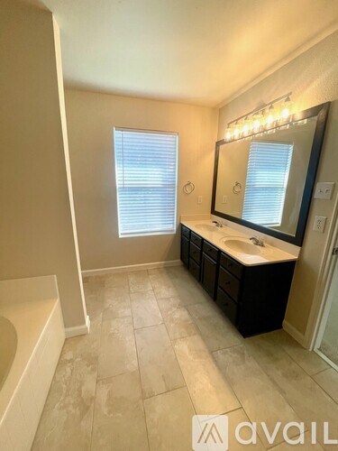 A bathroom with a tub, sink, and mirror.