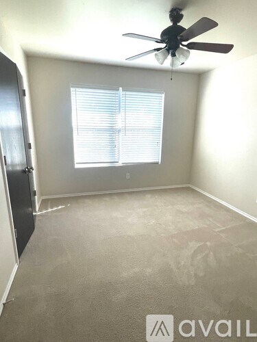 A room with a ceiling fan and a window with blinds.
