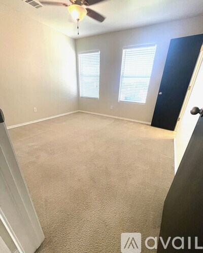 A room with a carpeted floor and a ceiling fan.