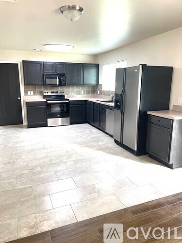 A kitchen with black cabinets and a refrigerator.