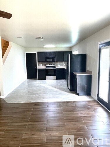 A kitchen with black cabinets and a wooden floor.