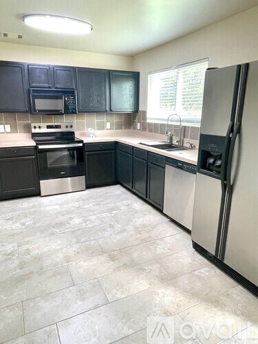 A kitchen with black cabinets and a white refrigerator.