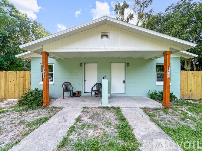 A small house with a porch and two chairs.