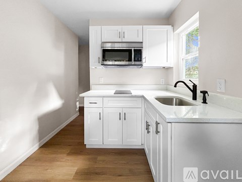 A kitchen with white cabinets and a stainless steel sink.