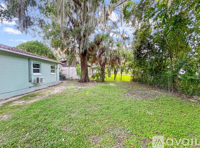 A backyard with a green lawn and trees.