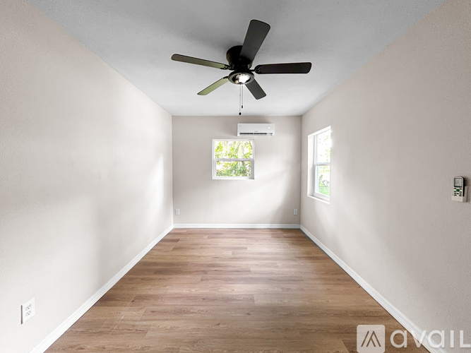 A room with a ceiling fan and wooden flooring.