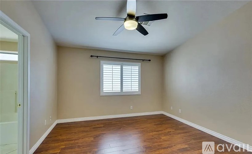 A room with a ceiling fan and a window with blinds.