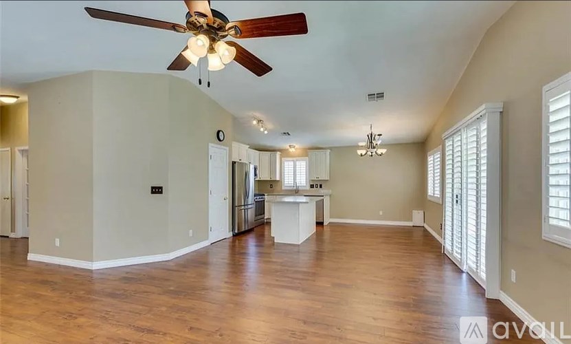 A spacious room with a ceiling fan and wooden flooring.