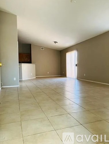 A spacious room with beige tiled flooring and a white door.
