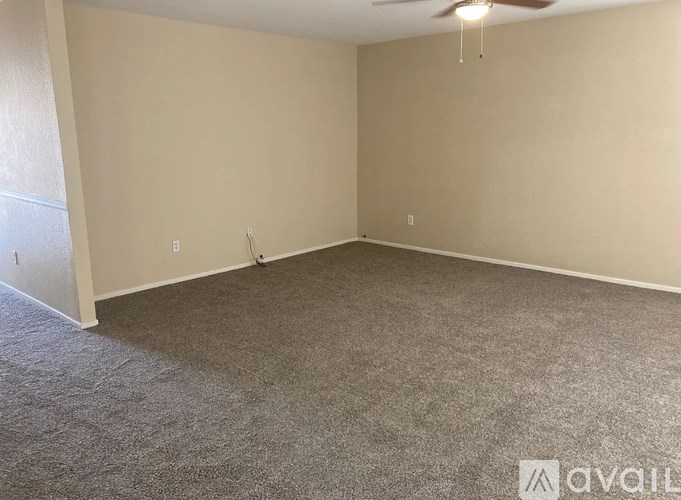 A room with a carpeted floor and a ceiling fan.