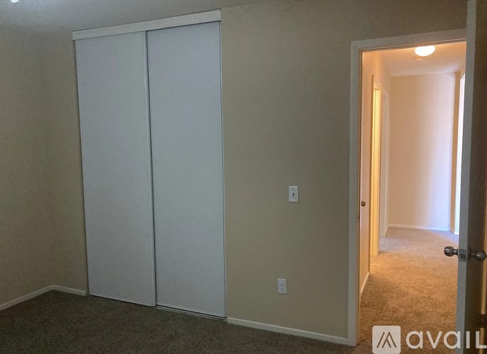 A room with a white door and a carpeted floor.