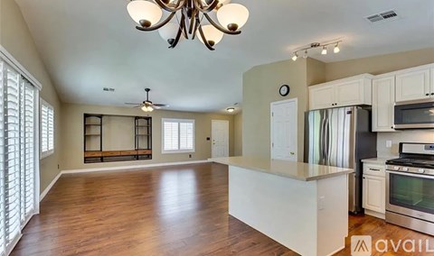 A spacious kitchen with white cabinets and a wooden floor.