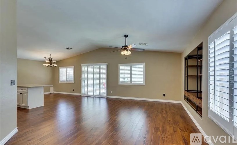 A spacious room with wooden floors and a ceiling fan.