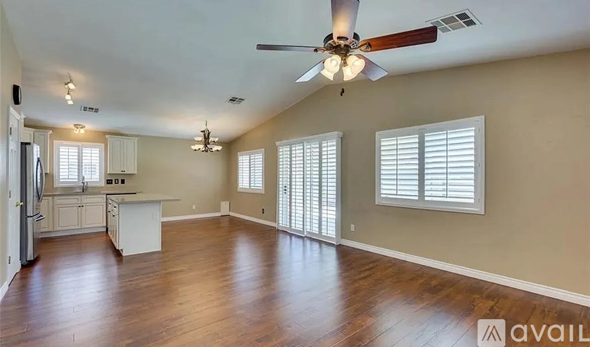 A spacious living room with a ceiling fan and hardwood floors.