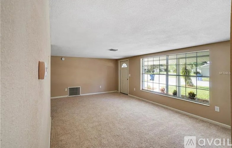 A spacious room with wooden floors and a ceiling fan.