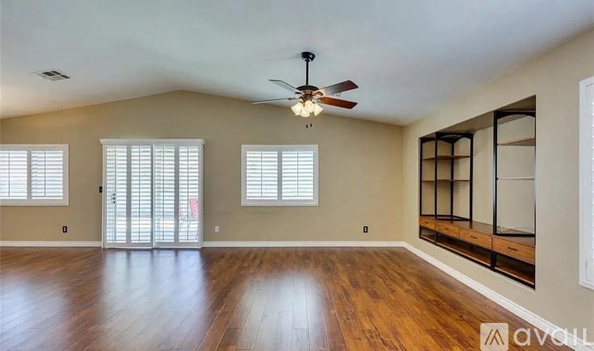 A spacious room with wooden floors and a ceiling fan.