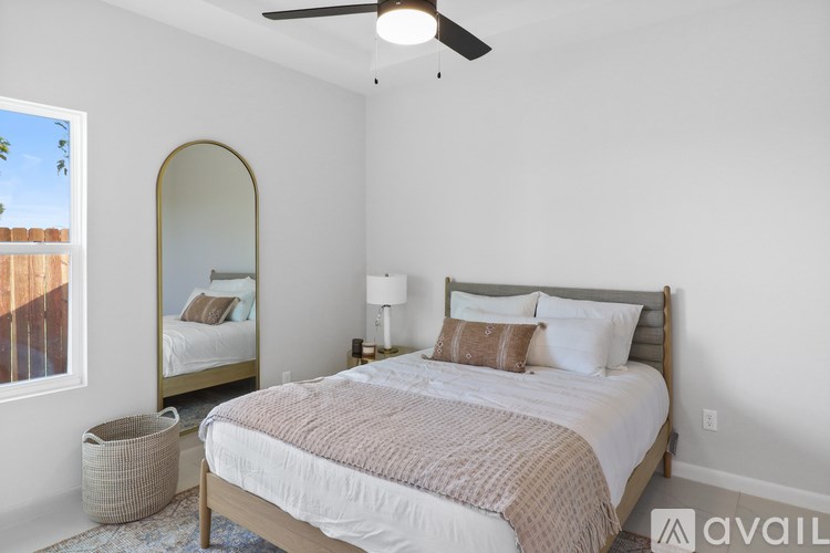 A bedroom with a bed, a mirror, and a ceiling fan.