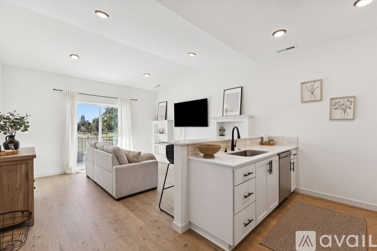 A modern kitchen with white cabinets and a large window.