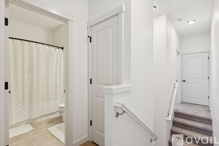 A white hallway with a staircase and a door.