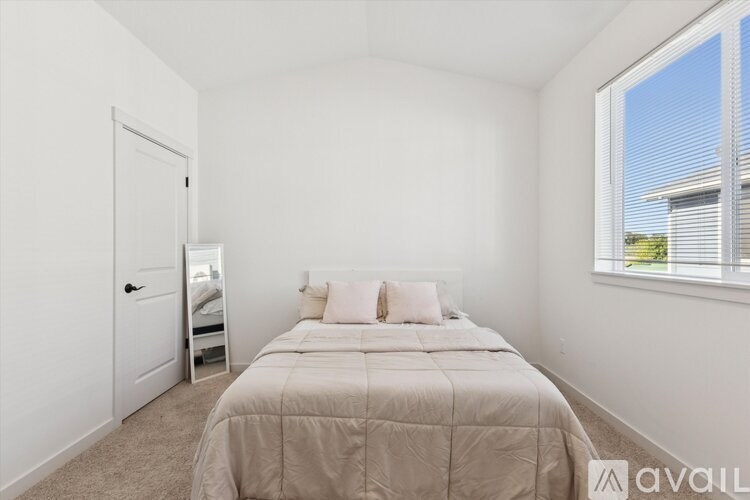 A bedroom with a bed, a nightstand, and a window.