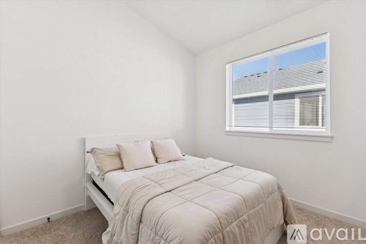 A bedroom with a bed, pillows, and a window with blinds.